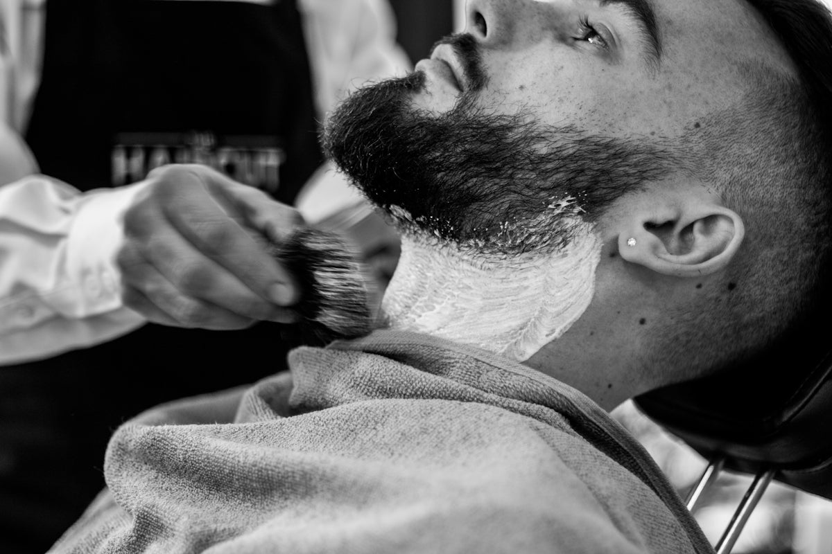 grayscale photo of man shaving his beard Image