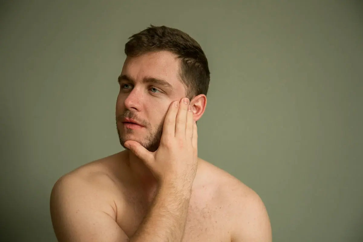 topless man covering his face with his hand Image