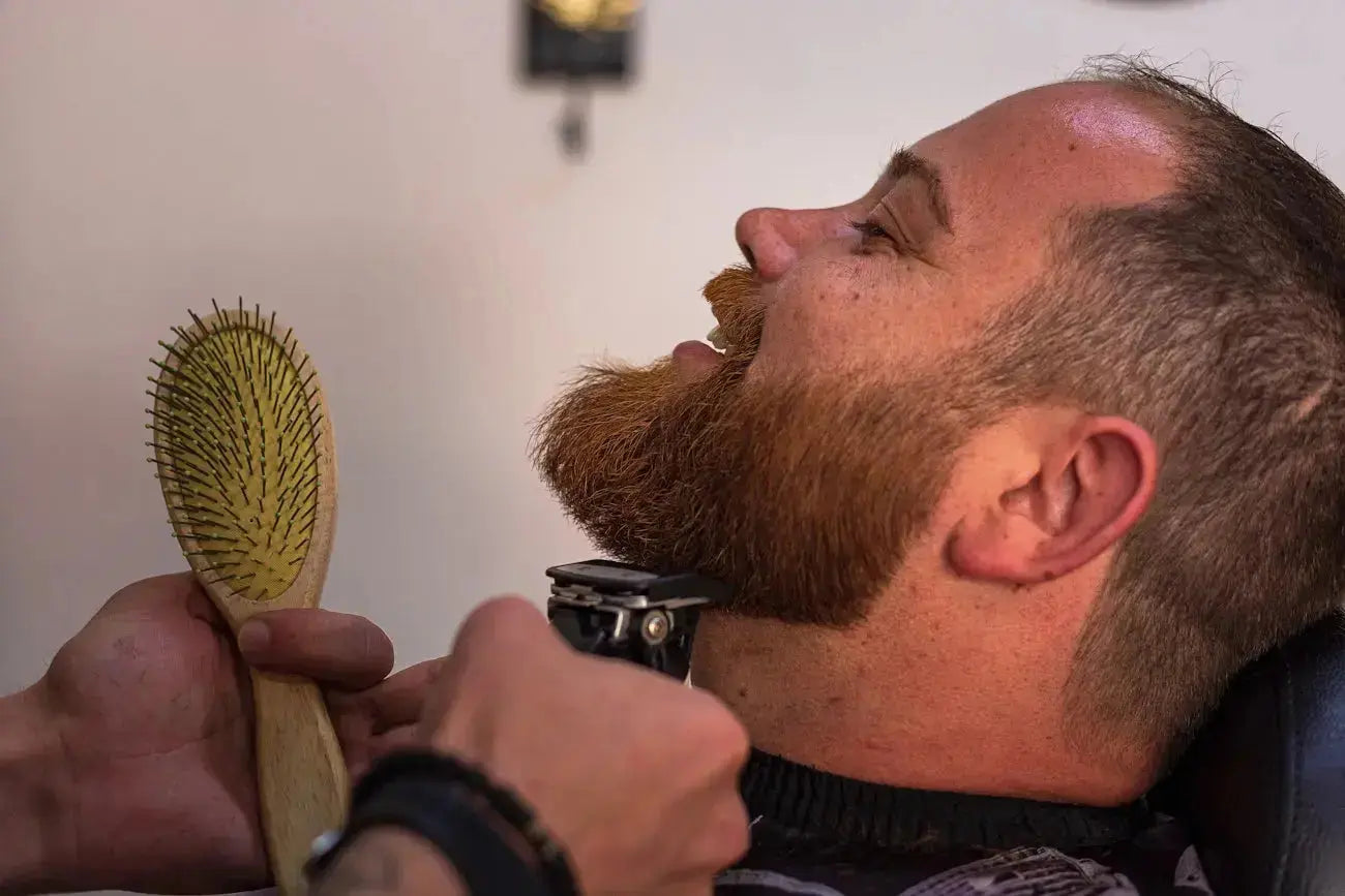 a bearded man getting his hair cut with a brush Image
