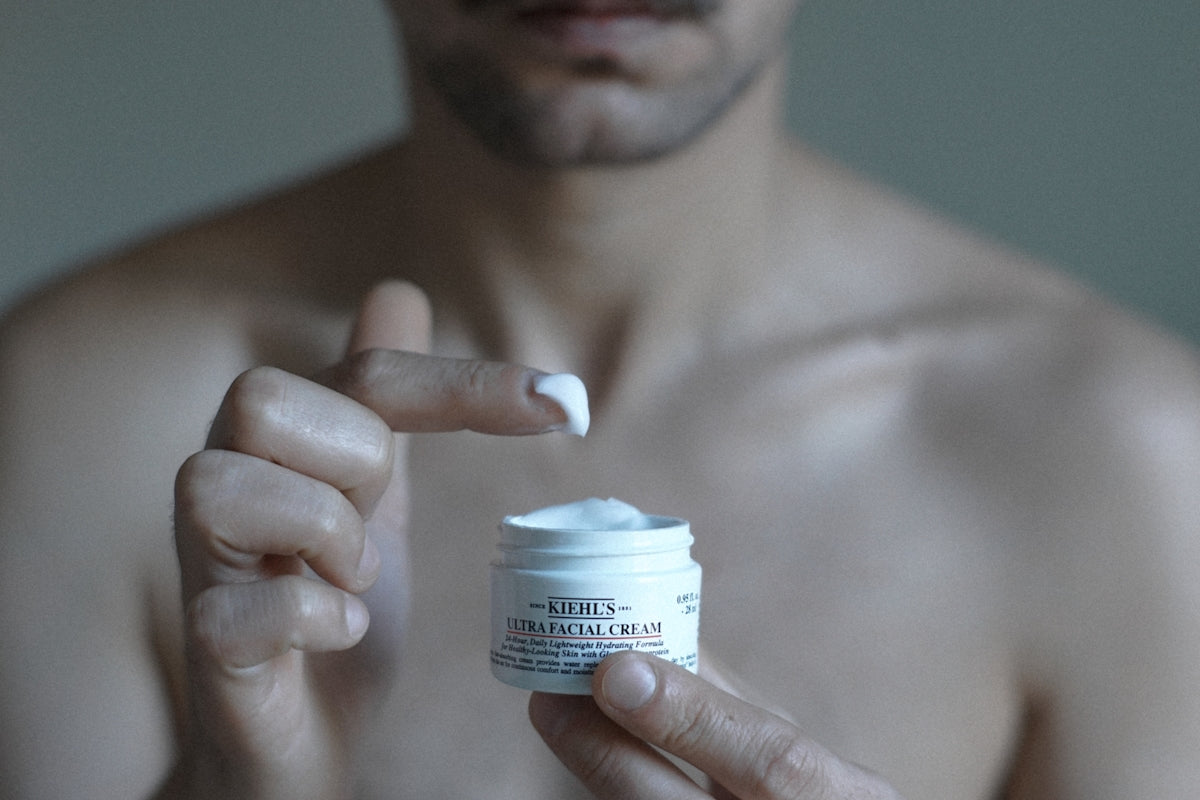 a man holding a jar of cream in his hand Image