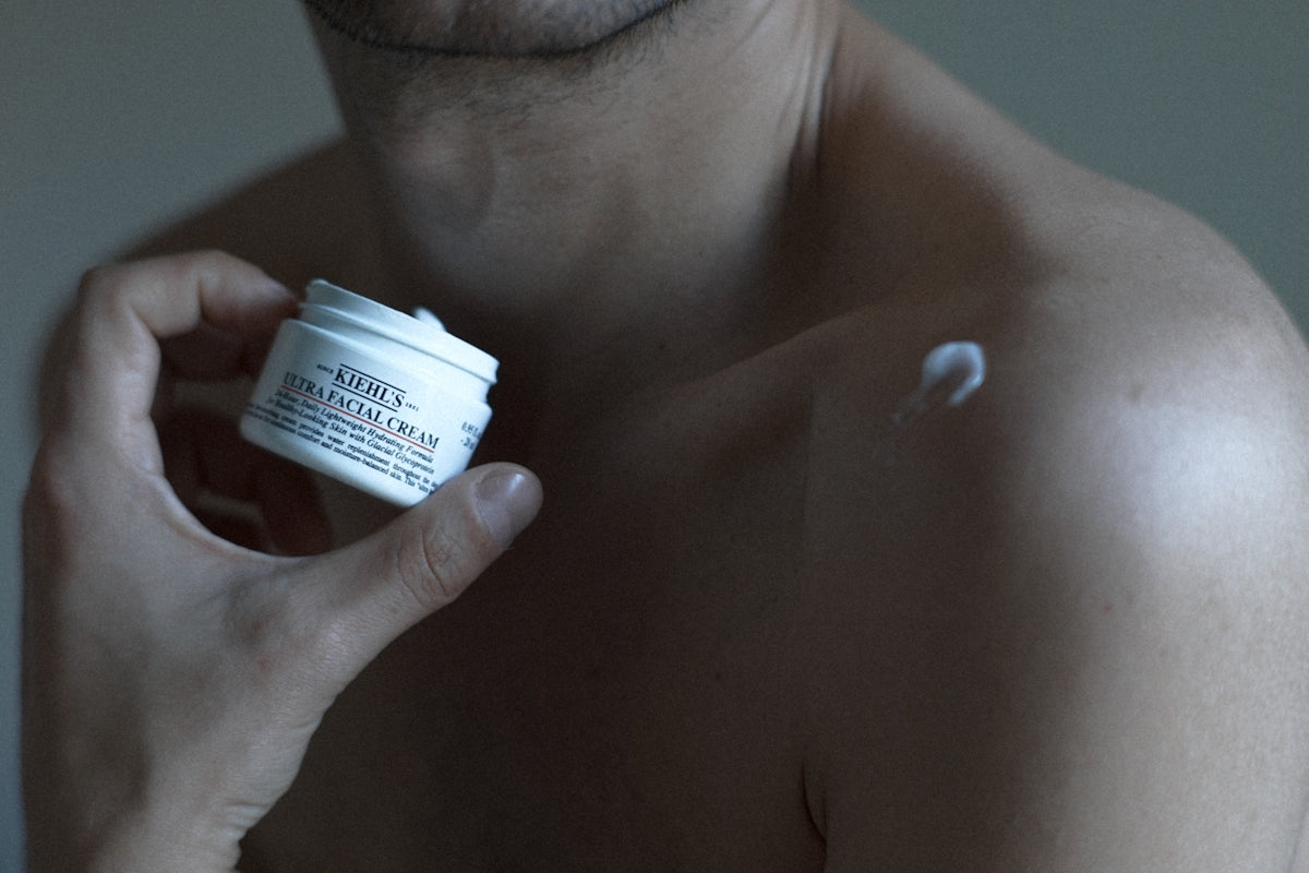 a man holding a jar of cream in his hand Image