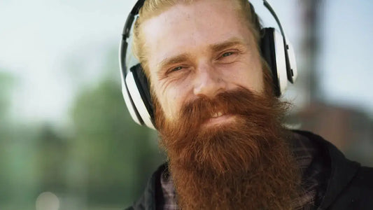 Man with headphones and a large beard smiles.