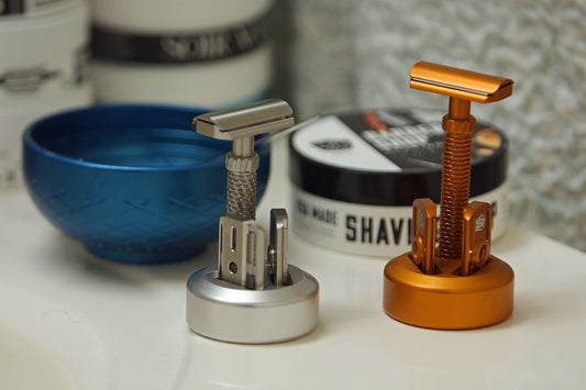 Two safety razors on stands with shaving cream.